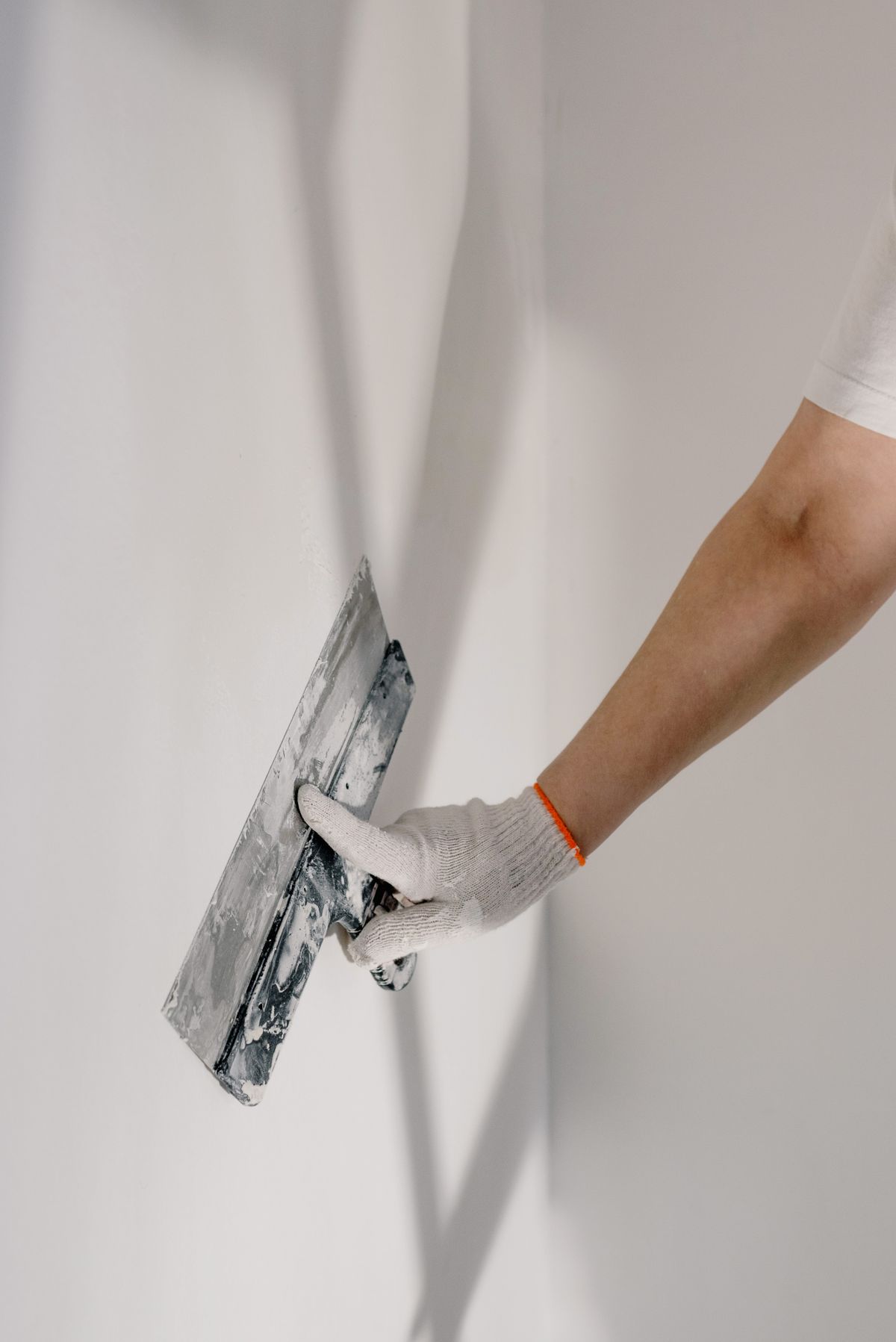 Worker finishing drywall with a taping knife