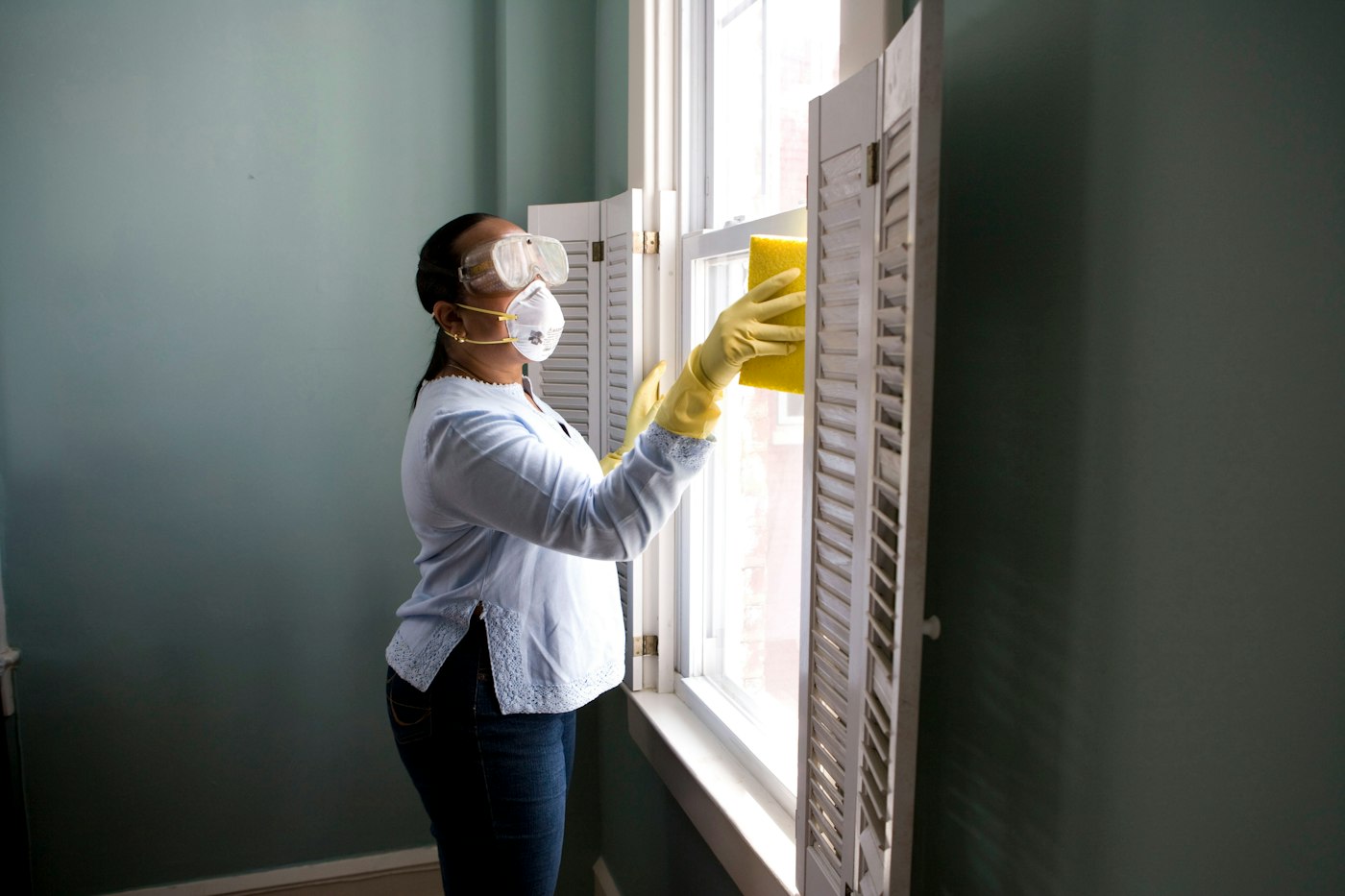Worker in PPE cleaning an interior surface