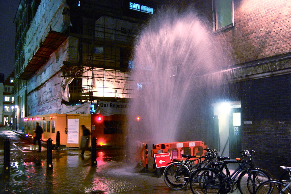 Nighttime water main break spraying into the street